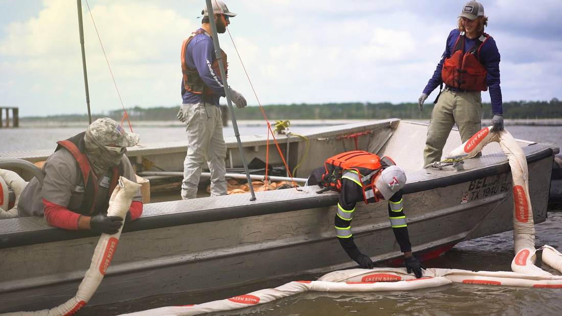 Crew deploying Green Boom booms from a boat